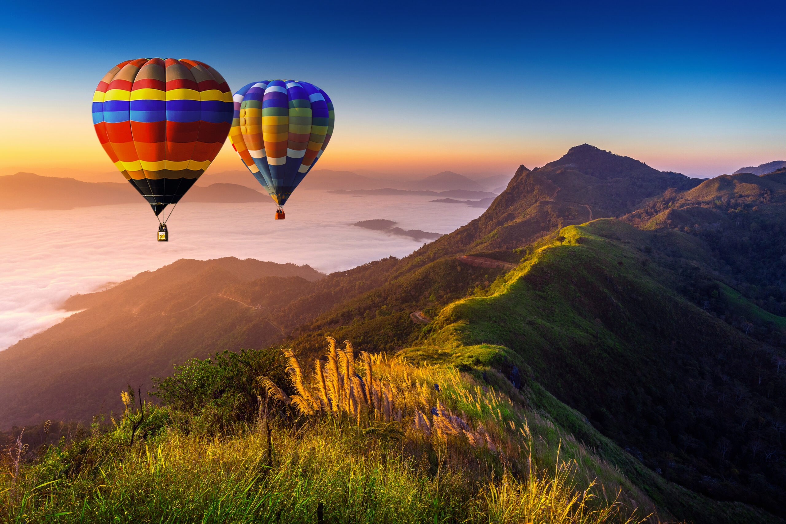 Landscape of morning fog and mountains with hot air balloons at sunrise.